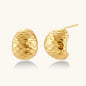 Pair of textured gold-plated sterling silver huggie earrings with dimpled surface finish on cream background.
